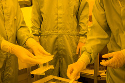 Drei Jugendliche, die mit Schutzkleidung ausgerüstet sind, führen ein Experiment durch und stellen einen Mikrochip her.