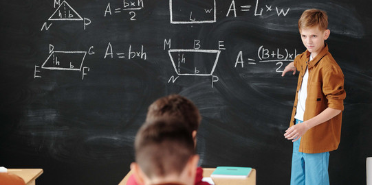 Ein Junge steht an der Tafel und erklärt Mathe